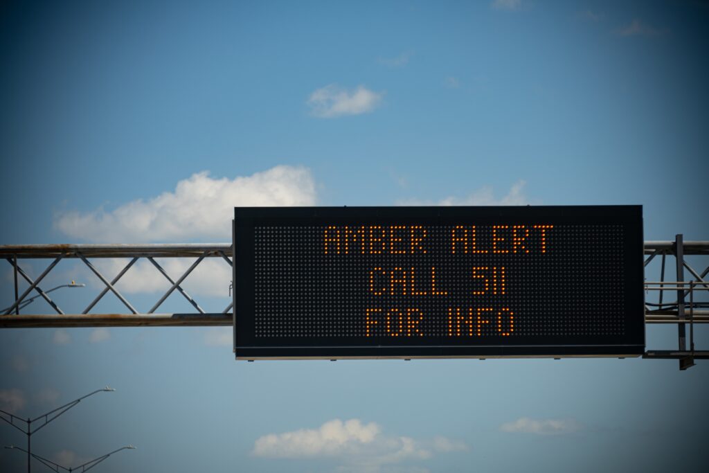 A digital sign above a busy highway alerts drivers to a current Amber Alert.