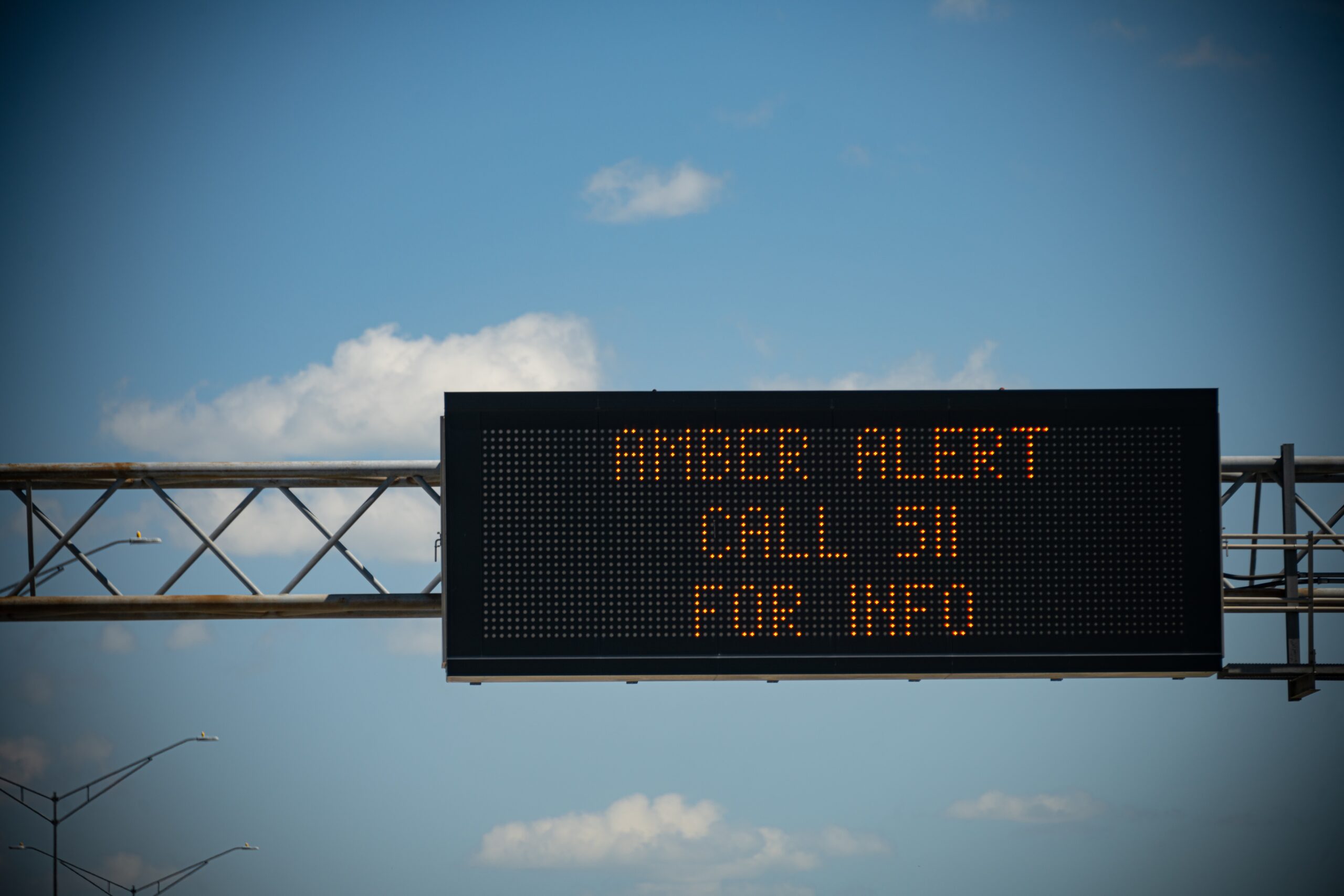 A digital sign above a busy highway alerts drivers to a current Amber Alert.